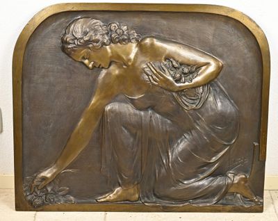 a bronze plaque of a woman with a basket of flowers
