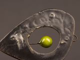 a metal sculpture with a green apple in it