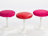 three red and white stools sitting next to each other on a white surface