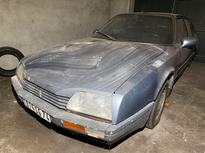 a dirty car in a garage with a tire in the background