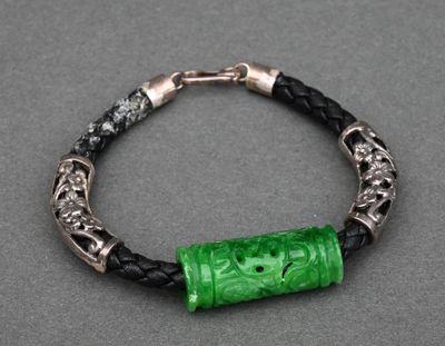 un bracelet composé d'une perle en verre verte montée sur un cordon en cuir noir