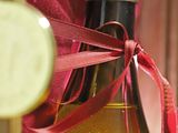 a bottle of wine that is wrapped in a red ribbon
