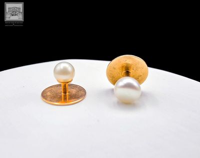 une paire de boucles d'oreilles à clous en perles et en or sur un fond blanc