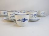 six blue and white cups and saucers are lined up on a white surface