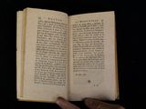 someone is holding an open book in their hand on a black surface