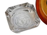 a glass ashtray with a logo on it next to a glass ashtray with a logo on it