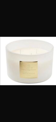 a close up of a white candle with a gold label on it