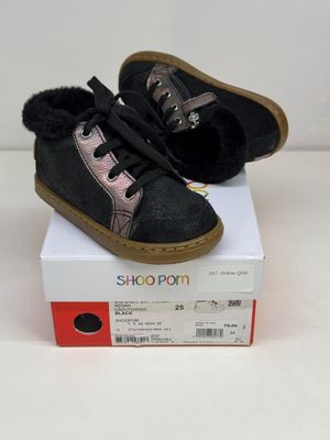 une paire de chaussures noires et roses posée sur une boîte blanche