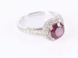 a close up of a ring with a red stone surrounded by white diamonds