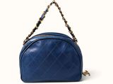 a blue handbag with a chain strap on a white background