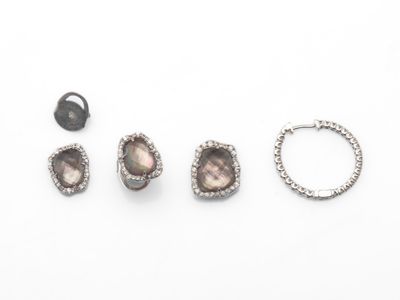 trois paires de boucles d'oreilles, une bague et une bague posées sur un fond blanc