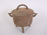 an old iron pot with a handle on a stand