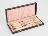 quatre couteaux dans un coffret en bois posé sur une surface blanche
