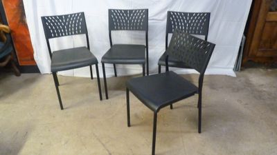 four black metal chairs sitting in front of a white backdrop