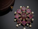 une photo d'une broche ornée de perles et de pierres roses