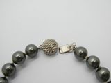 un gros plan sur un collier de perles noires muni d'un fermoir en argent