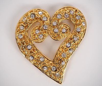 a close up of a heart shaped brooch on a white surface
