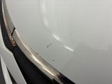 a close up of a white car with a rusted bumper