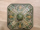 a green and brown square shaped object on a wooden table