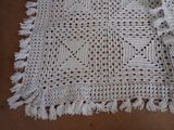 a white crocheted table cloth with tassels on it