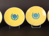 four yellow plates with blue designs on them on a black surface