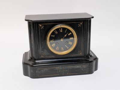 a small black clock with a gold face on a white background