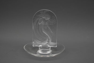 une figurine en verre transparent représentant une femme posée sur un plateau