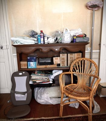 an image of a cluttered room with a chair and bookshelf