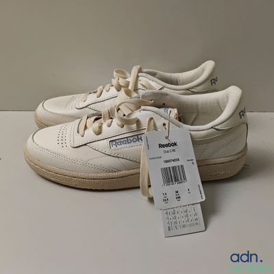 a pair of white sneakers with a price tag on them