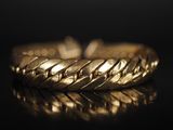gros plan d'un bracelet en or sur une surface noire