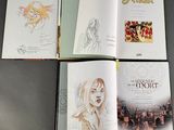 four books with drawings of a woman on them sitting on a table