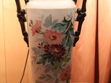a white vase with flowers on it sitting on a table