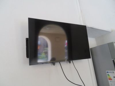 une télévision à écran plat fixée au mur à côté d'un réfrigérateur