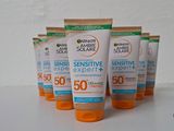 quatre tubes de crème solaire posés sur une surface blanche