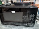 un micro-ondes noir posé sur une étagère métallique dans un magasin
