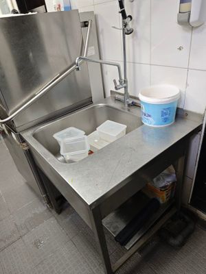 un évier en inox dans une cuisine avec une poubelle posée sur le plan de travail