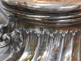 a close up of a silver vase on a table