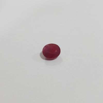 an oval red ruby gems on a white surface