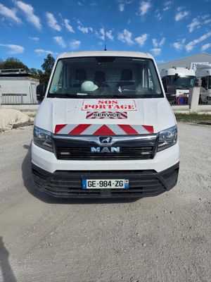 La camionnette est garée sur le chemin de terre devant un immeuble.