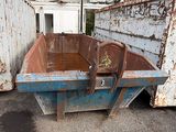 une benne à ordures rouillée abandonnée sur un parking
