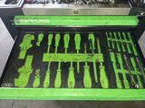 une boîte à outils verte posée par terre, contenant des outils