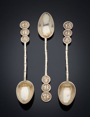 three silver spoons and two silver spoons on a black surface