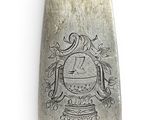 a silver spoon with a design on it on a white surface