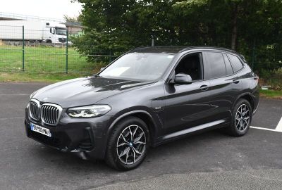 La BMW X3 est garée sur un parking près d'une clôture