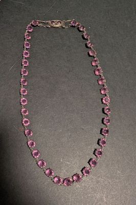 un collier composé d'une perle violette et d'une chaîne en argent