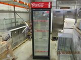 a coca cola cooler in the middle of a warehouse