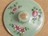 a green plate with pink flowers on it on a table