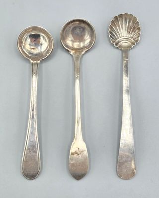 trois cuillères en argent et deux cuillères en argent sur une table