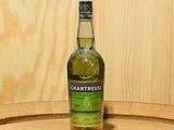 une bouteille de Chartreuse posée sur un tonneau