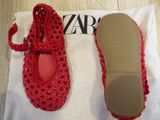 pair of red crocheted shoes on a white cloth on a table